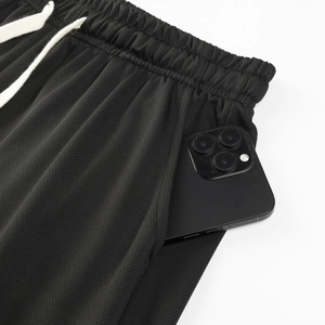 Detail of black mesh sports shorts featuring a deep side pocket with a smartphone inside