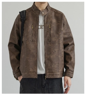 Dettaglio della giacca vintage in ecopelle marrone con cerniere metalliche e borchie
