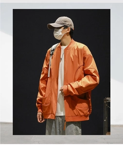 Detail shot of bright orange bomber jacket featuring functional 3D cargo pockets and stand collar