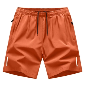 Detail view of orange sports shorts with drawstring waist, zipper pockets and reflective strips