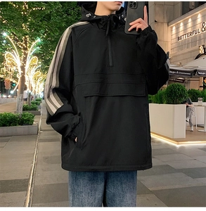 Detail of black hooded anorak jacket with gray shoulder stripes and front large pocket