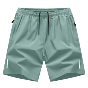 Detail of sage green sports shorts showing elastic waistband and zipper pockets