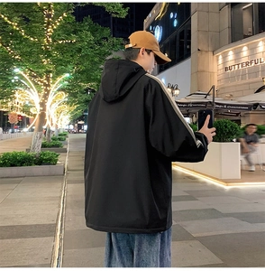 Rear view of an oversized black hooded jacket with striped sleeves and streetwear styling