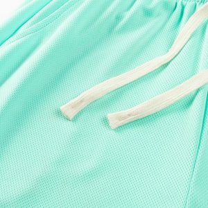 Close-up of mint green breathable mesh sports shorts with elastic drawstring waistband