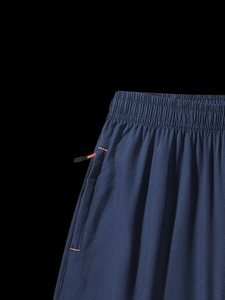 Detail of elastic waistband and side zip pocket with orange trim on navy sports shorts