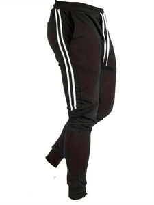 Détail d'un pantalon de jogging noir avec bandes blanches latérales et ourlets élastiques