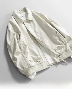 Flat lay of beige windproof jacket showing rib cuffs, zipper pockets, and fabric texture