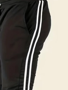 Détail d'un pantalon de sport noir avec deux bandes blanches verticales sur le côté