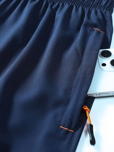 Macro detail of blue quick-dry shorts featuring an elastic waist and zipper pocket with orange puller