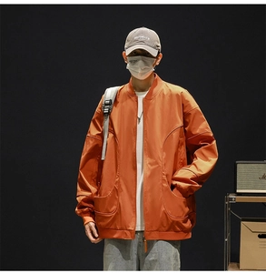 Close-up of orange men's baseball jacket featuring large utility pockets and water-resistant fabric