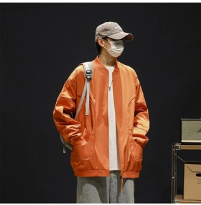 Close-up of an oversized orange baseball bomber jacket with ribbed collar and shoulder pleats