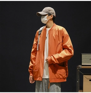 Detail of orange baseball jacket featuring large curved pockets and ribbed cuffs