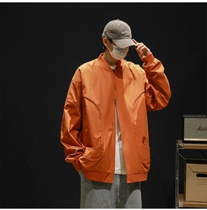 Detail of orange men's bomber jacket featuring baseball collar and curved seam stitching