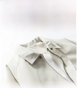 Detailed close-up of cream jacket lapel featuring metal zipper and snap button closure