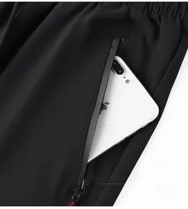 Detail of waterproof zipper pocket on men's black ice silk pants with smartphone storage