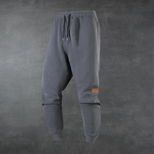 Close-up of charcoal gray fleece joggers with leather patch detail and ribbed ankle cuffs