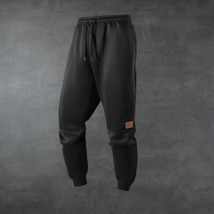 Detail of black men's joggers showing elastic waistband and brown leather patch accent