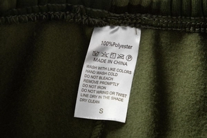 Close-up of garment care label showing 100% polyester material and size S on fleece pants