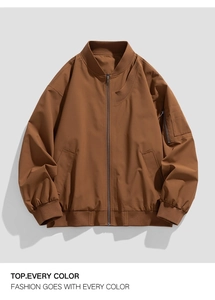 Detail of caramel brown bomber jacket with ribbed collar and utility sleeve pocket