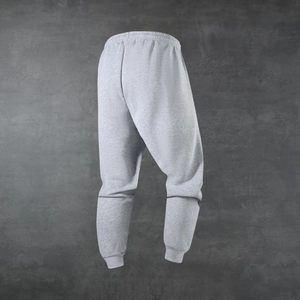 Detail of grey men's joggers showing elastic waistband and ribbed cuffs on textured background