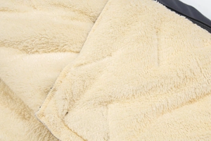 Detail shot of the thick beige faux fur lining and black fabric on winter jacket