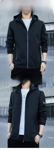 Détail de la veste coupe-vent noire à capuche avec poches zippées et écusson sur la manche