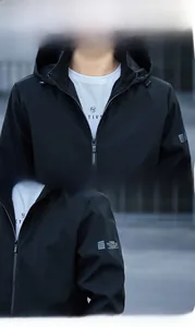 Détails du col à capuche et de l'imprimé sur la manche d'une veste coupe-vent noire