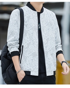 Close-up of white baseball jacket featuring grey monstera leaf print and black ribbed edges