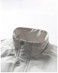 Detail of off-white outdoor jacket featuring a stand collar and matte snap buttons