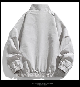 Rear view of light grey outdoor jacket featuring elastic hem and raglan sleeve design
