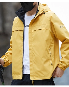Detail of yellow waterproof outdoor jacket featuring zip pockets and fashion print