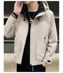 Detail view of the contrasting zipper and utility pocket on this beige hooded jacket