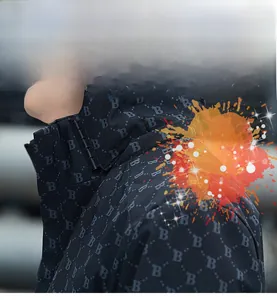 Dettaglio della tecnologia antimacchia su giacca con cappuccio ed effetto spruzzo arancio