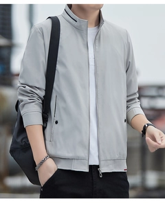 Detail of light gray bomber jacket with ribbed cuffs and stand collar showing fabric texture