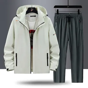 Set sportivo da uomo con giacca a vento color crema e pantaloni sportivi grigio scuro