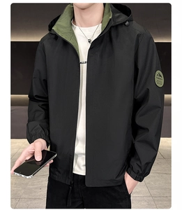 Close-up of black hooded jacket featuring contrast lining and outdoor badge on the sleeve