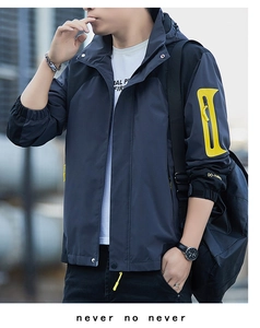 Detail of dark grey waterproof jacket featuring yellow arm pocket and elastic cuffs