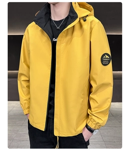 Detail of a bright yellow hooded jacket featuring a mountain patch and elastic cuffs