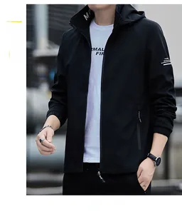 Detail of men's black hooded windbreaker jacket with white logo print on the left sleeve