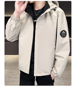 Detail of light beige hooded jacket with circular mountain patch on the sleeve