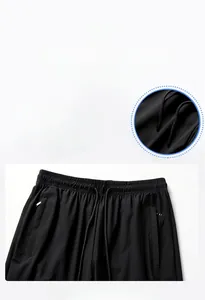 Detail view of black ice silk pants showing elastic drawstring waist and zipper pockets