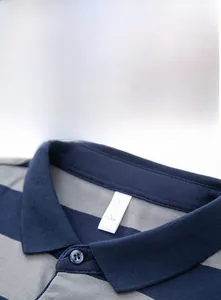 Détail macro du col en maille classique et boutons bleus sur un polo à rayures
