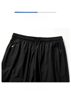 Detail of black sports pants showing elastic waistband with drawstring and zipper pocket