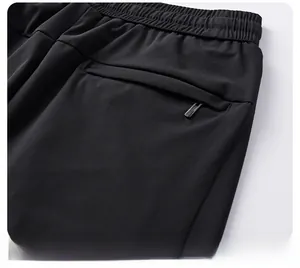 Detail view of the elastic waistband and secure zippered back pocket on black track pants
