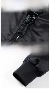 Detailed view of the metal zipper and elastic ribbed knit cuffs on a black bomber jacket