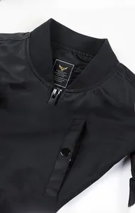 Detail view of black bomber jacket featuring ribbed collar and secure snap pocket