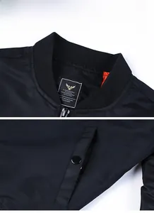 Detail of black bomber jacket with ribbed collar, orange lining and snap button pocket