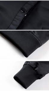 Detailed macro view of black bomber jacket with ribbed cuffs and metallic button pocket