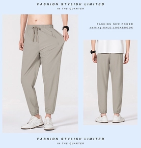 Detailed view of elastic drawstring waist and functional zipper pockets on light grey pants