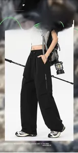 Detail of loose black outdoor cargo pants with waterproof fabric and drawstring waist